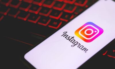Smartphone exibe o logo e o nome do aplicativo Instagram sobre teclado com iluminação vermelha.
