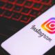Smartphone exibe o logo e o nome do aplicativo Instagram sobre teclado com iluminação vermelha.