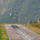 Pequeno avião bimotor em aproximação para pouso em pista curta de aeroporto na montanha.