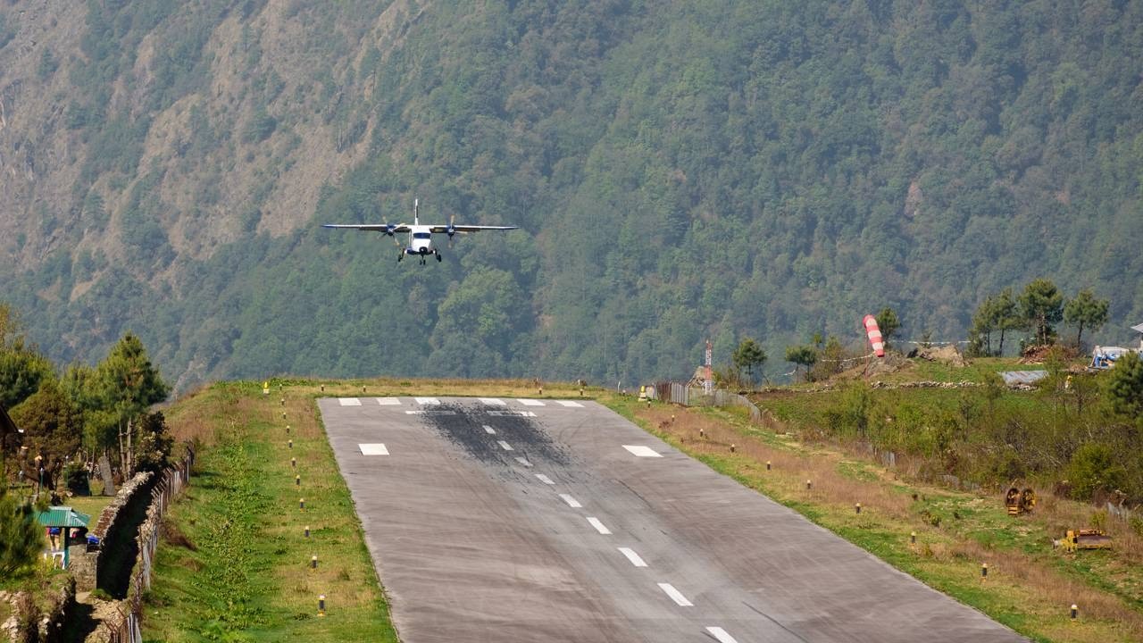 Pequeno avião bimotor em aproximação para pouso em pista curta de aeroporto na montanha.