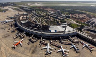 Vista aérea do terminal do Aeroporto Internacional do Galeão com múltiplos aviões e veículos de apoio em pátio.