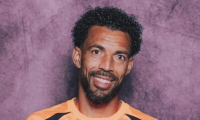 Retrato de Josimar Dias, o Vozinha, sorrindo com cabelo crespo, barba e camisa laranja.