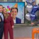 Estúdio de TV. Alan Severiano, Jacqueline Brazil e colega com balões, festa em telão.