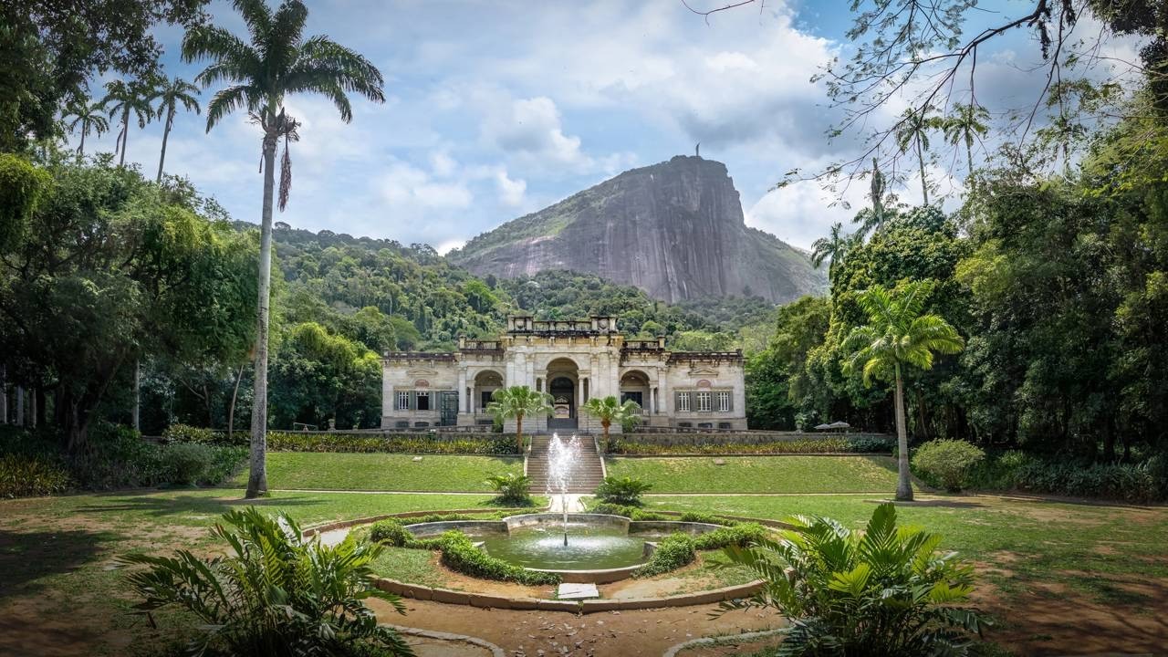 Palacete histórico no Parque Lage com fonte e montanha Corcovado ao fundo, Rio de Janeiro.