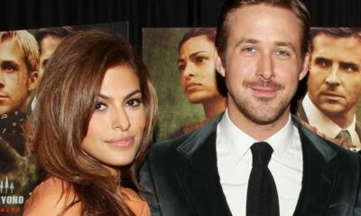 Ryan Gosling e Eva Mendes posando, sorrindo. Pôsteres de filmes em segundo plano.