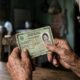 Mãos envelhecidas segurando uma carteira de identidade brasileira antiga com foto de jovem.