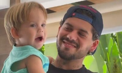 Zé Felipe sorrindo segura o filho José Leonardo, criança com boca aberta