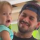Zé Felipe sorrindo segura o filho José Leonardo, criança com boca aberta