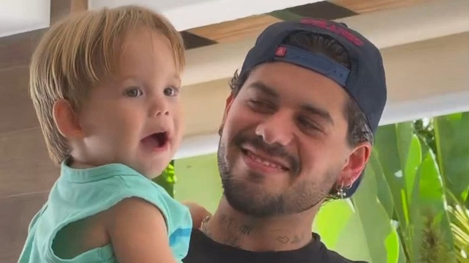 Zé Felipe sorrindo segura o filho José Leonardo, criança com boca aberta