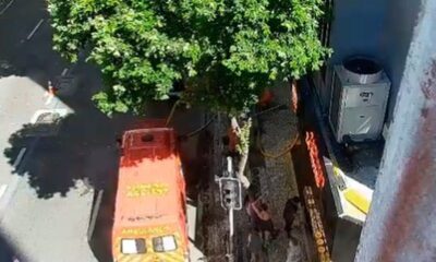 Ambulância laranja ‘AMBULÂNCIA ASSIST’ na rua, pessoas, árvore, unidade de ar condicionado