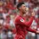 Cristiano Ronaldo celebra em campo com camisa vermelha, apontando os dedos para cima e à frente