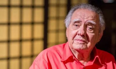 Luiz Carlos Barreto, homem idoso com cabelo grisalho e camisa vermelha, olhando pensativo