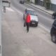 Homem em vermelho na calçada, carro prateado ao lado. Poste com sinal "8:00HS. AS 17:30HS".