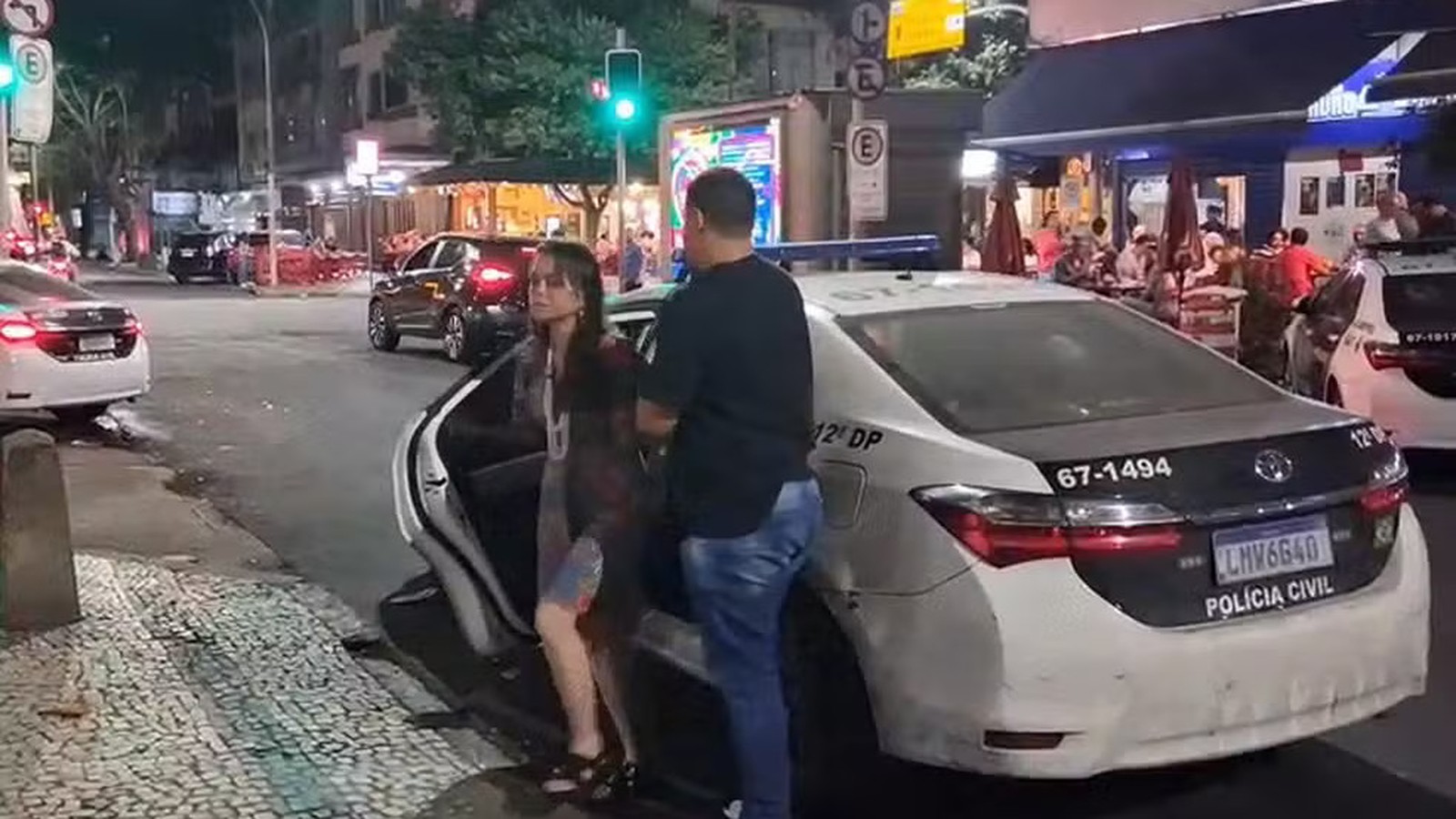 Agente da Polícia Civil coloca mulher em viatura policial à noite, com '12ª DP'