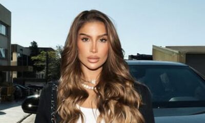 Bianca Andrade com cabelo castanho ondulado, maquiagem, colar de pérolas, ao ar livre