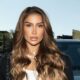 Bianca Andrade com cabelo castanho ondulado, maquiagem, colar de pérolas, ao ar livre