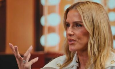 Close-up de mulher loira (Deborah Secco) gesticulando com a mão direita enquanto fala em entrevista