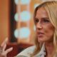 Close-up de mulher loira (Deborah Secco) gesticulando com a mão direita enquanto fala em entrevista