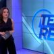 Apresentadora Márcia Dantas em estúdio, roupa preta, tablet nas mãos, tela "Tempo Real" ao fundo