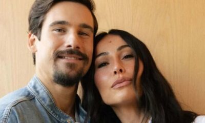 Nicolas Prattes e Sabrina Sato sorrindo em close-up, com a cabeça dela apoiada no ombro dele