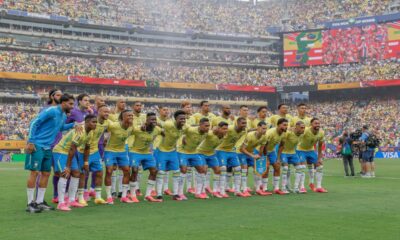 Time de futebol do Brasil posa em campo com telões exibindo 'FIFA World Cup 2026', 'Brazil' e 'Norway'.