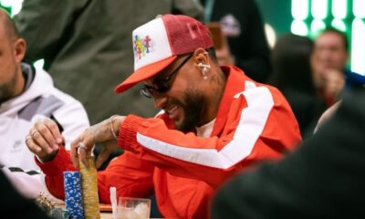 Neymar Jr sorrindo, de boné e óculos, empilhando fichas de pôquer em uma mesa de jogo