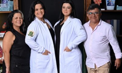 Quatro pessoas, mãe, pai e duas filhas de jaleco branco, sorrindo para a câmera
