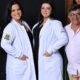 Quatro pessoas, mãe, pai e duas filhas de jaleco branco, sorrindo para a câmera