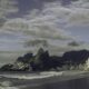 Praia com ondas, prédios da cidade e montanhas sob céu nublado no Rio de Janeiro
