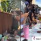 Pessoas em churrasco ao ar livre, com homem na grelha e convidados à mesa em São Gonçalo