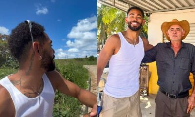 Jogador Matheus Cunha com mecânico Denílson sorrindo e em paisagem com céu azul e vegetação