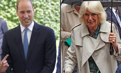 Príncipe William sorri de terno; Rainha Camilla sorri de trench coat sob guarda-chuva.