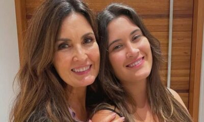 Duas mulheres sorrindo para a câmera, com cabelos castanhos longos