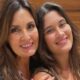Duas mulheres sorrindo para a câmera, com cabelos castanhos longos
