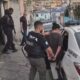 Policiais escoltam mulher algemada para viatura da DEAM-NIG em operação policial