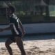 Virginia Fonseca de biquíni sorrindo, com raquete de beach tennis, Vini Jr. correndo na areia