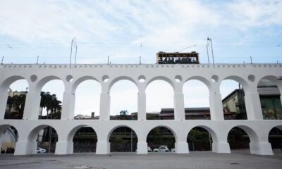 Arcos da Lapa brancos com bonde amarelo sobre a estrutura e céu azul