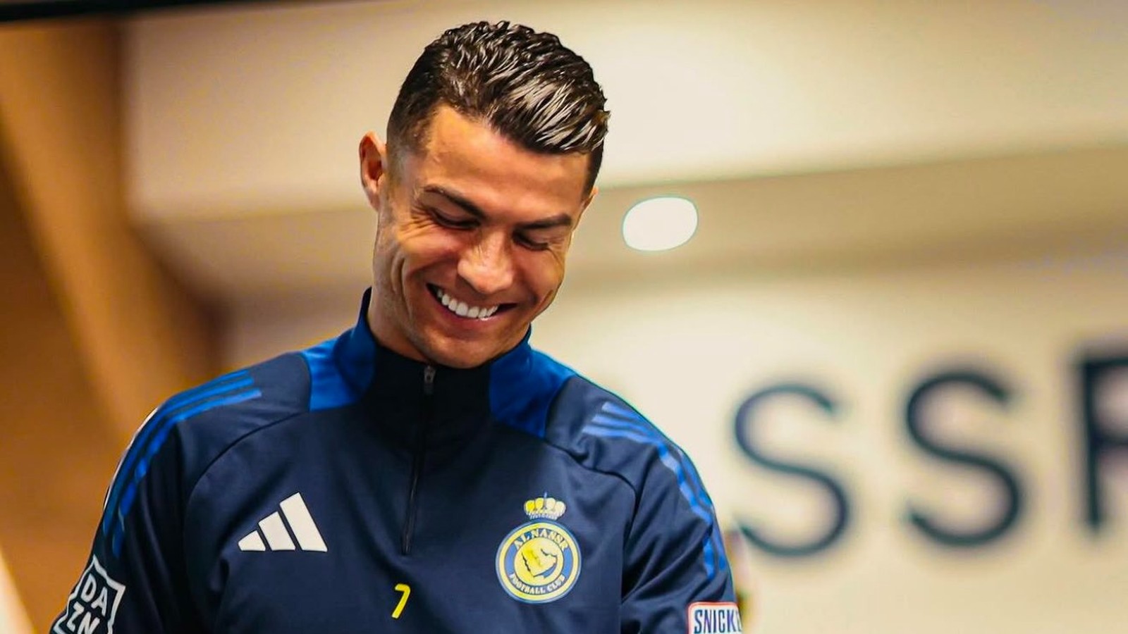 Cristiano Ronaldo sorri usando agasalho azul com o logo do Al Nassr