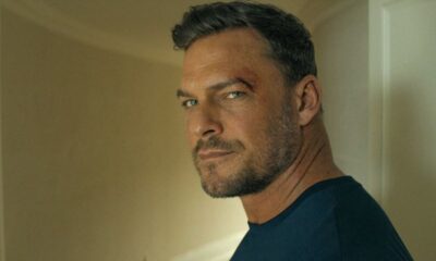 Alan Ritchson com barba e arranhão na testa, olhando para a câmera.