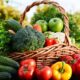 Cesta de vime com brócolis, maçãs verdes, pimentões, tomates e outros vegetais frescos