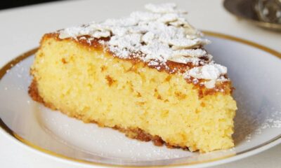 Fatia de bolo amarelo com cobertura de açúcar de confeiteiro e amêndoas laminadas em um prato