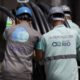 Trabalhadores com capacetes e uniformes 'Águas do Rio' e 'Rio Service' manuseiam tubos