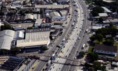 Vista aérea da movimentada Avenida Brasil com carros, caminhões e edifícios industriais