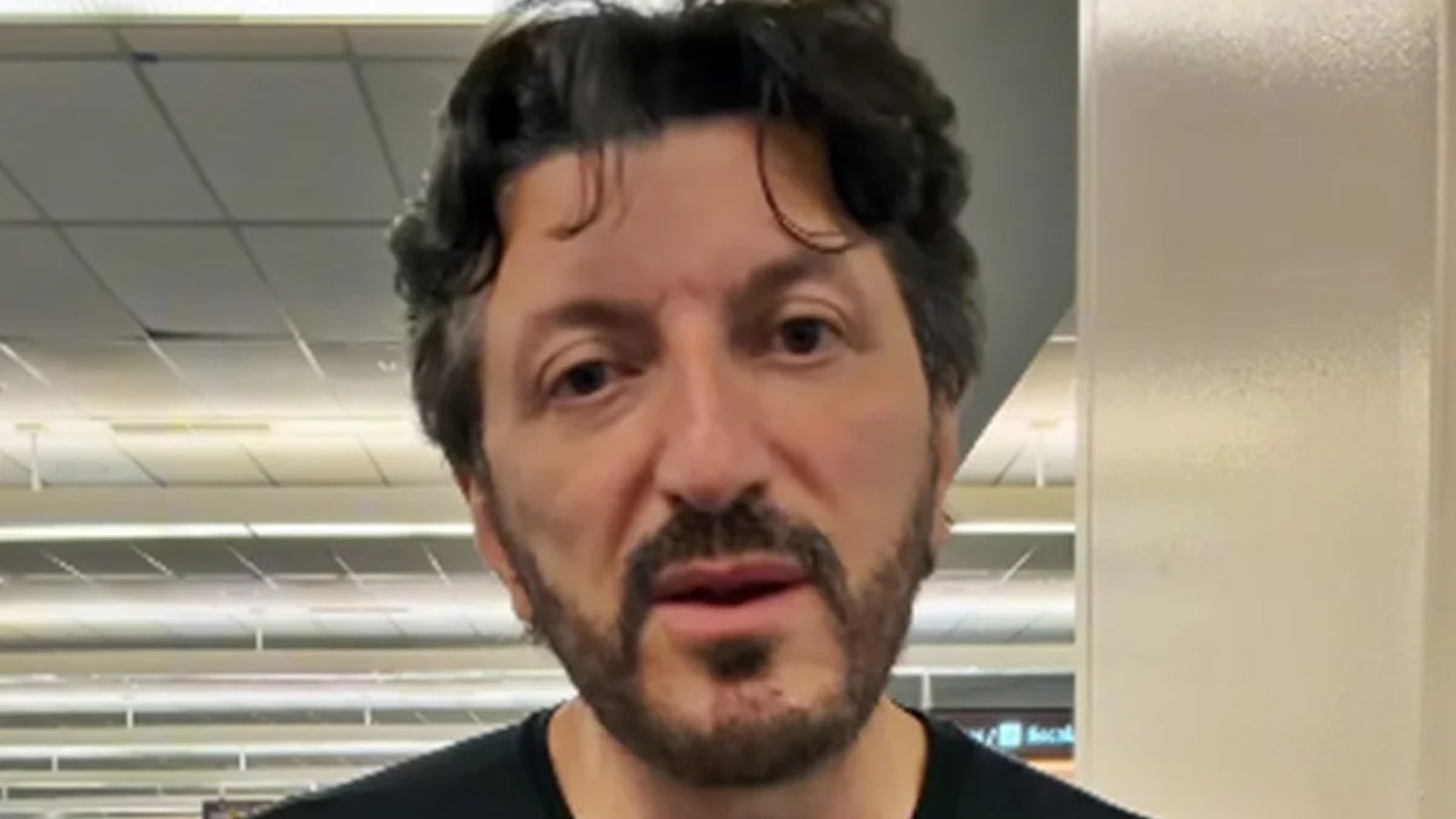Close do influenciador Lito Sousa, barba e cabelo escuros, olhando para frente em ambiente interno