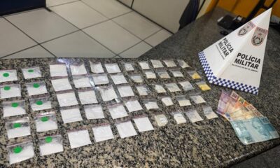 Drogas em sacolas, notas de dinheiro e placa da Polícia Militar sobre bancada