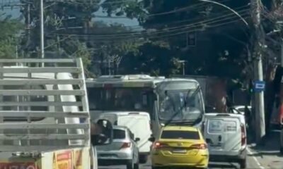 Trânsito intenso com ônibus, caminhão, van, carro e táxi amarelo em rua urbana