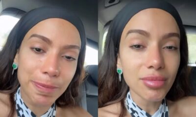 Anitta, com faixa preta, lágrimas nos olhos e brincos de esmeralda, em close-up de emoção