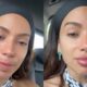 Anitta, com faixa preta, lágrimas nos olhos e brincos de esmeralda, em close-up de emoção