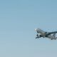 Avião branco de passageiros decolando em um céu azul claro