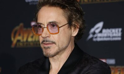 Robert Downey Jr. em close-up, usando óculos de armação laranja e roxa